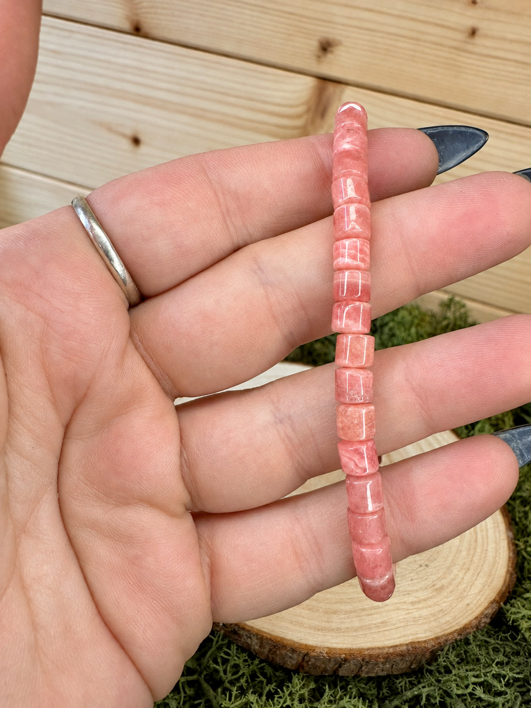 Close-up of polished pink Rhodochrosite bead bracelet showing natural banding
