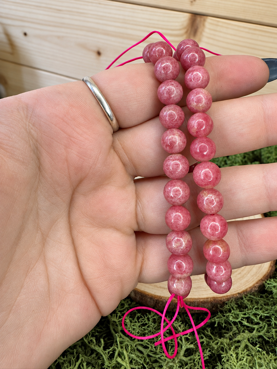 Close up of polished Sakura Rhodonite bracelet showing natural raspberry pink crystal beads
