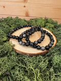 Three Silver Sheen Obsidian crystal bead bracelets displayed on natural wood